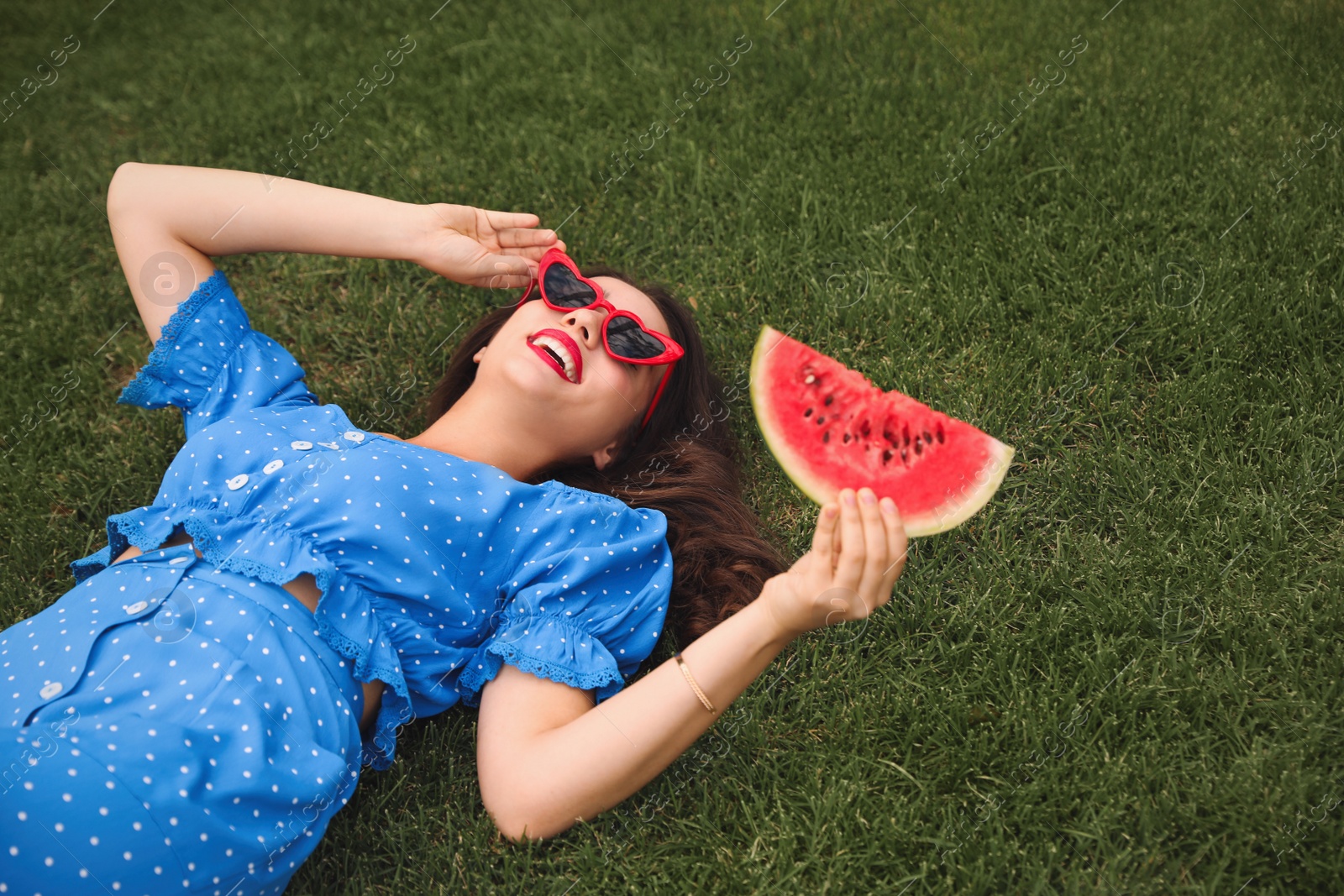 Photo of Beautiful young woman with watermelon on green grass outdoors