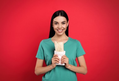 Happy young woman with delicious shawarma on red background