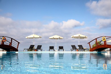 Photo of Chaise longues and beach parasols near outdoor swimming pool at resort