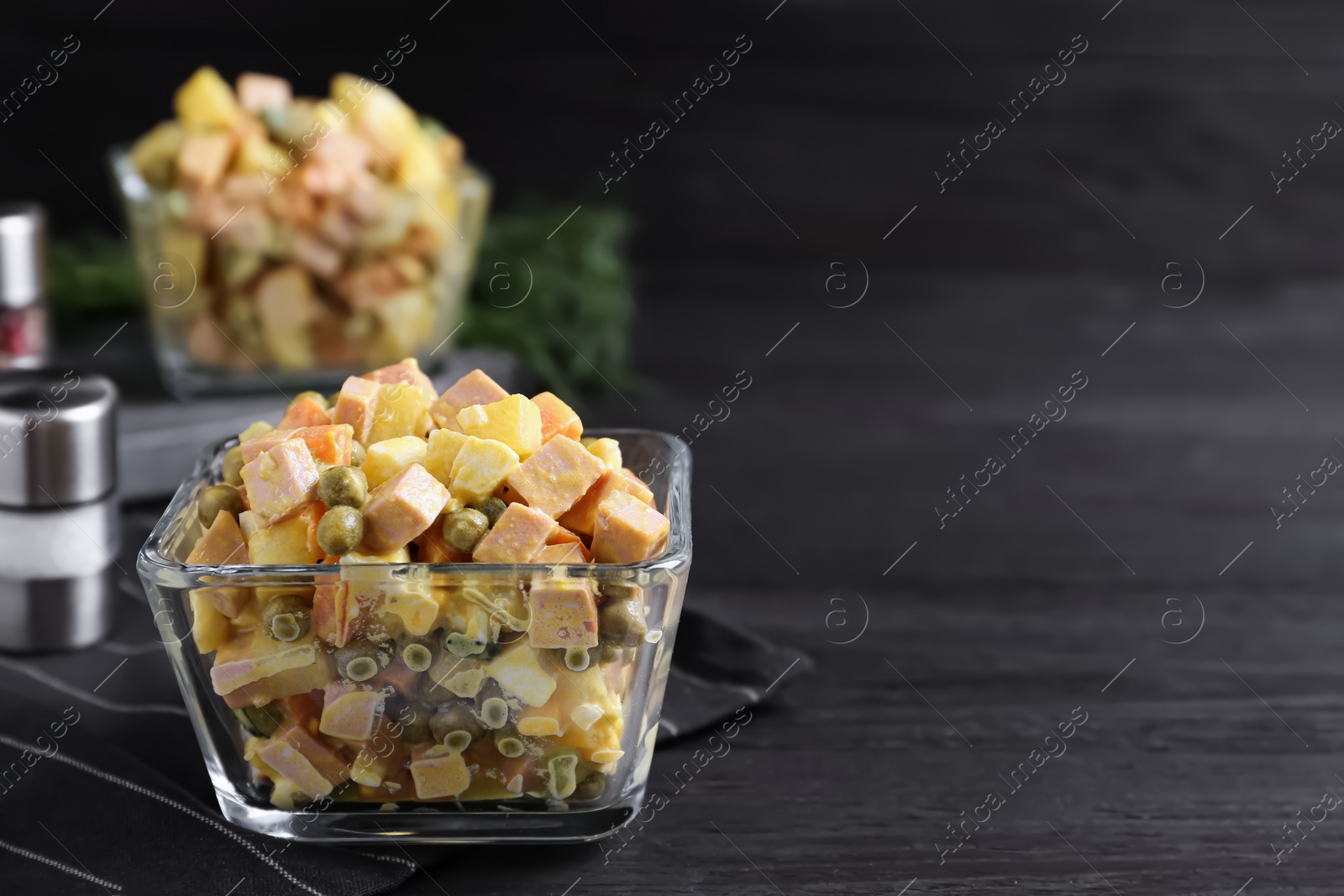 Photo of Delicious russian salad Olivier served on black wooden table. Space for text