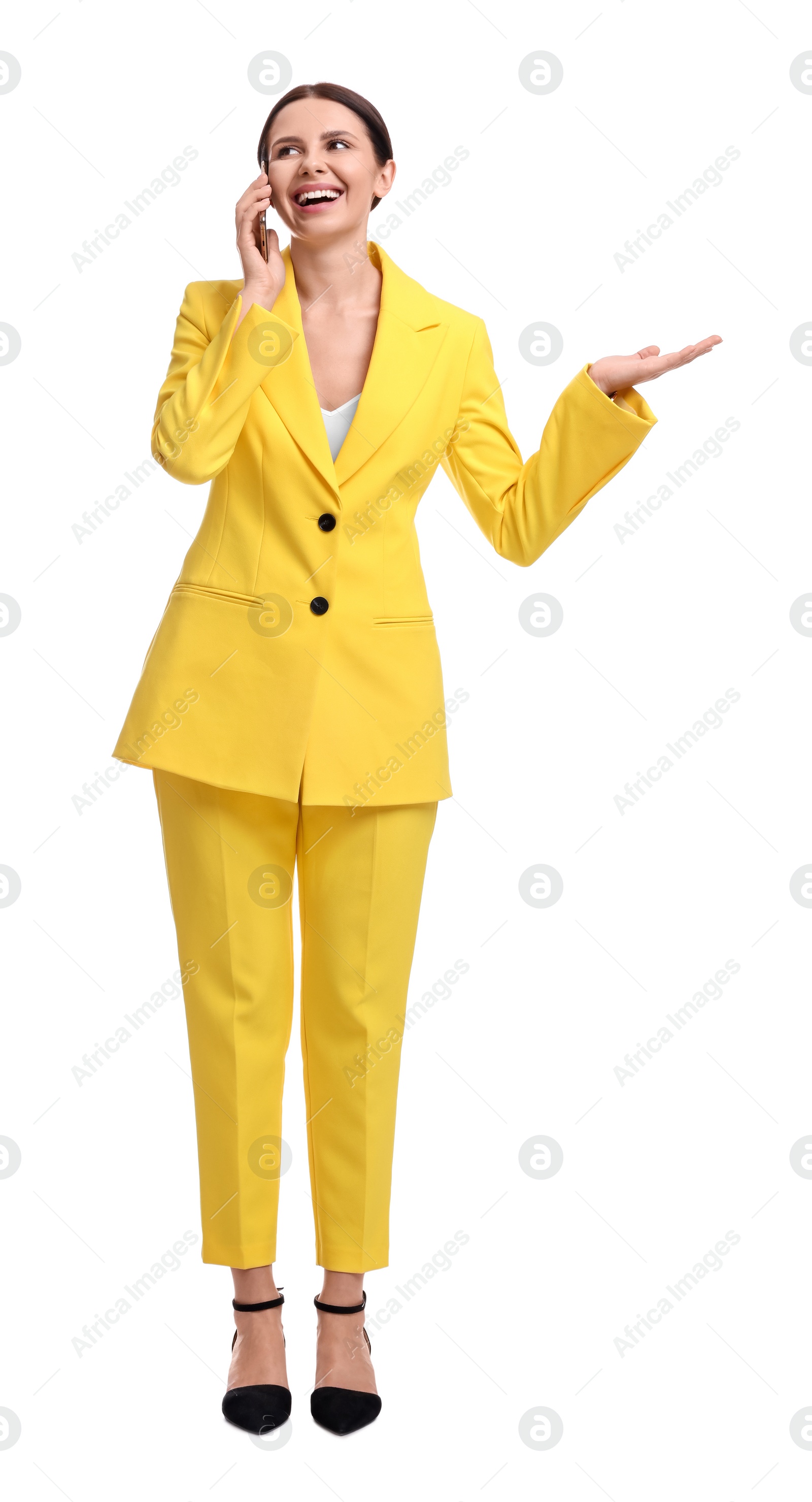 Photo of Beautiful businesswoman in yellow suit talking on smartphone against white background