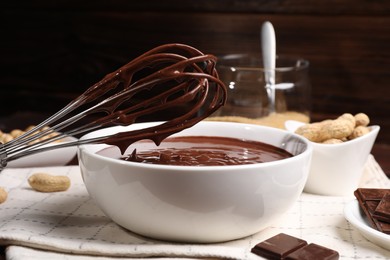 Photo of Bowl and whisk with chocolate cream on table