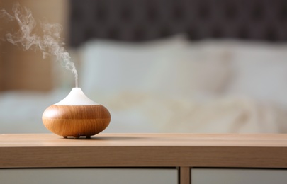 Photo of Aroma oil diffuser lamp on cabinet against blurred background