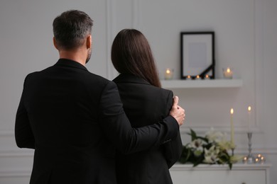Photo of Couple mourning indoors, back view and space for text. Funeral ceremony