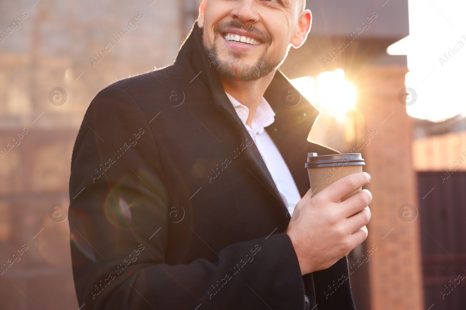 Photo of Man with cup of coffee on city street in morning, closeup