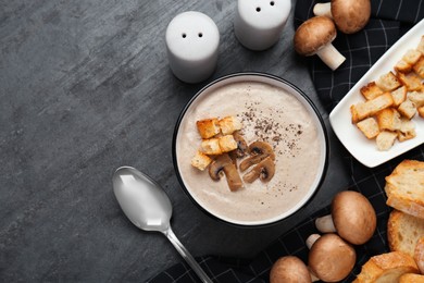Photo of Delicious cream soup with mushrooms and croutons on black table, flat lay. Space for text