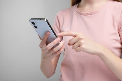 Photo of Woman sending message via smartphone on grey background, closeup