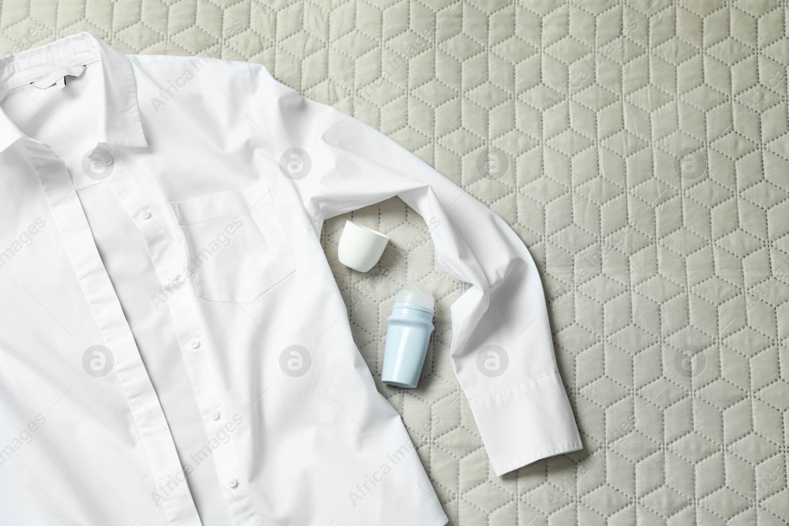 Photo of Roll-on deodorant and white shirt on light plaid, flat lay. Space for text