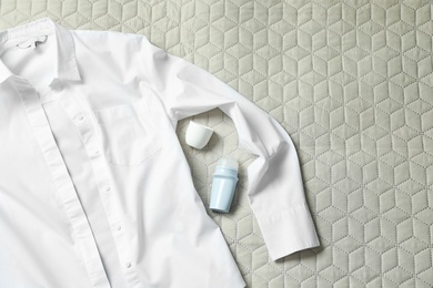 Photo of Roll-on deodorant and white shirt on light plaid, flat lay. Space for text