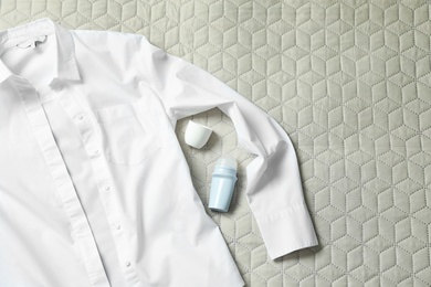 Roll-on deodorant and white shirt on light plaid, flat lay. Space for text