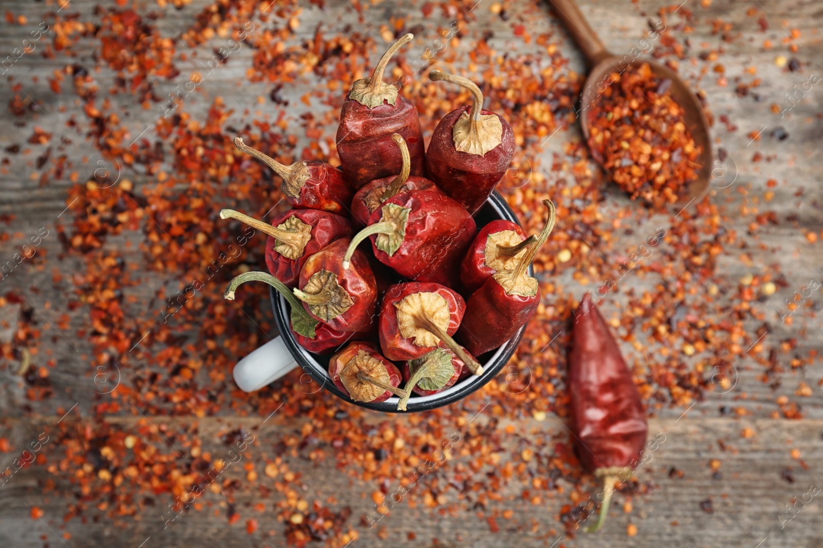 Photo of Mug with dry chili peppers and powder on wooden background