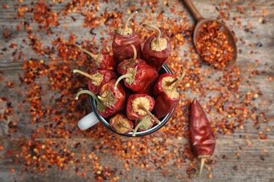 Photo of Mug with dry chili peppers and powder on wooden background