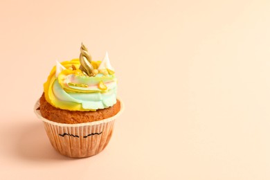 Photo of Cute sweet unicorn cupcake on beige background, space for text