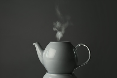 Photo of Ceramic teapot on warmer against grey background