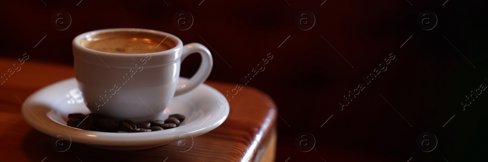 Image of Cup of hot aromatic coffee and roasted beans on wooden table in cafe, space for text. Banner design