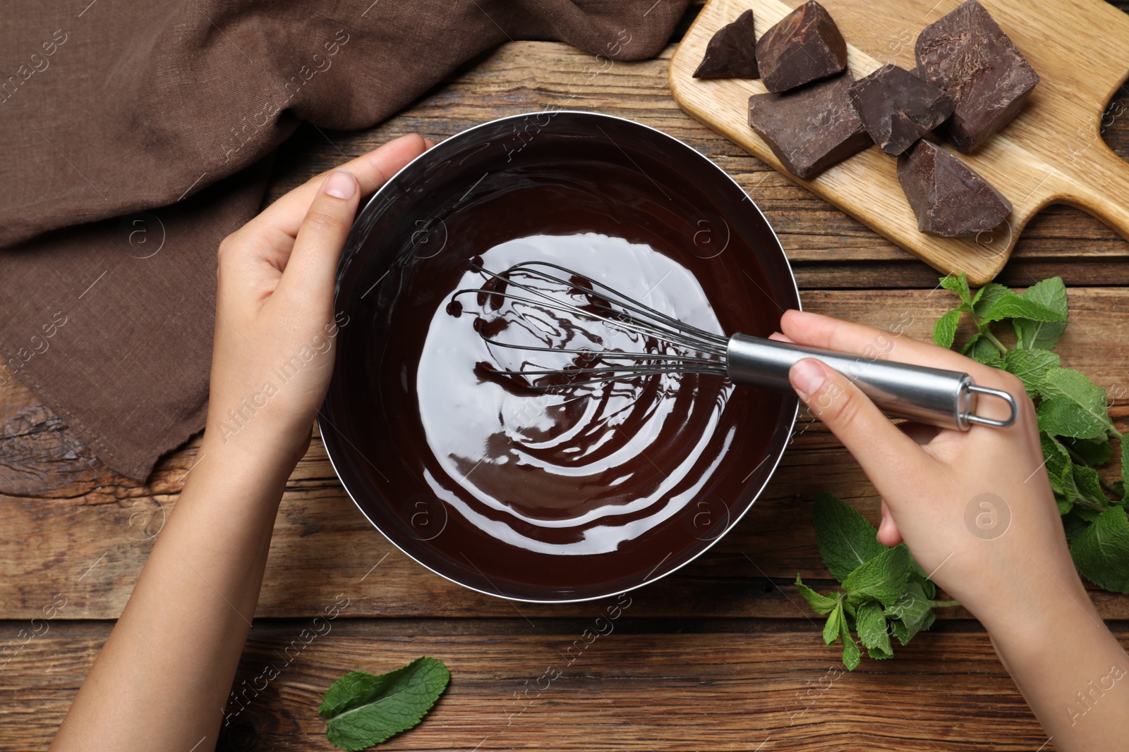 Photo of Woman making delicious chocolate cream at wooden table, top view