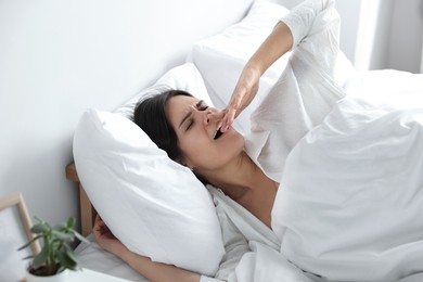 Photo of Sleepy young woman lying on soft pillow in bed at home