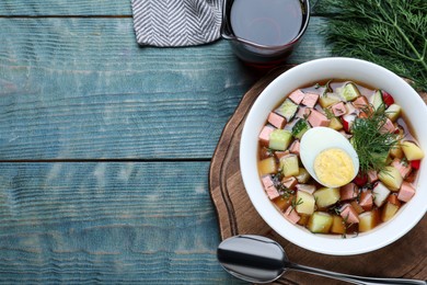 Photo of Delicious cold okroshka with kvass served on blue wooden table, flat lay and space for text. Traditional Russian summer soup