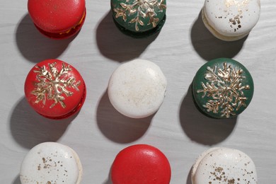 Different decorated Christmas macarons on wooden table, flat lay