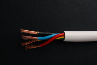 Cable with stripped wires on black background, closeup