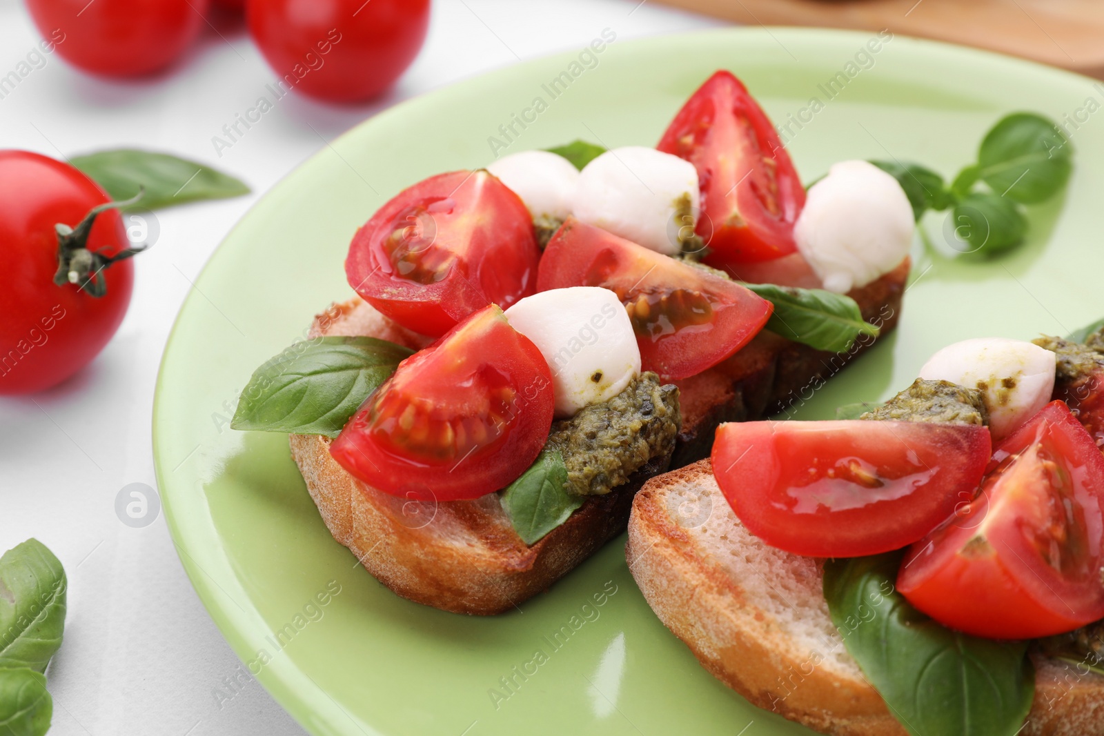 Photo of Delicious Caprese sandwiches with mozzarella, tomatoes, basil and pesto sauce on white tiled table, closeup