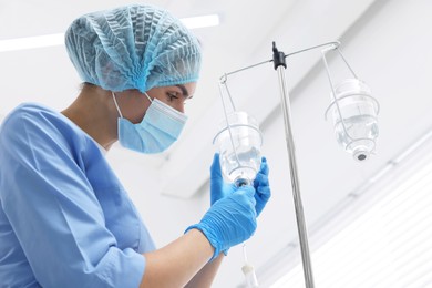 Nurse setting up IV drip in hospital, low angle view