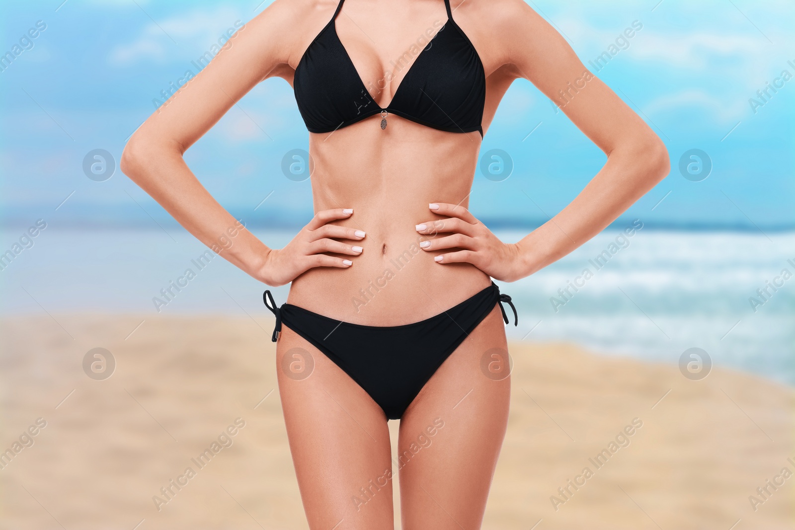 Image of Woman in stylish black bikini on sandy beach near sea, closeup