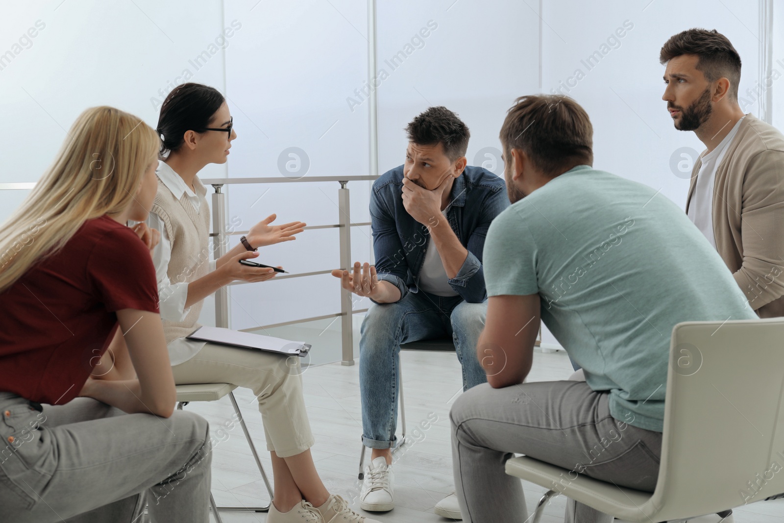 Photo of Psychotherapist working with group of drug addicted people at therapy session indoors