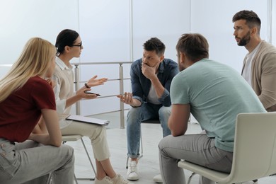 Photo of Psychotherapist working with group of drug addicted people at therapy session indoors