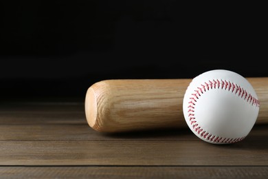 Photo of Baseball bat and ball on wooden table. Sports equipment