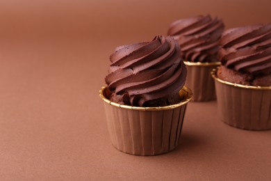 Photo of Delicious chocolate cupcakes on brown background, closeup. Space for text