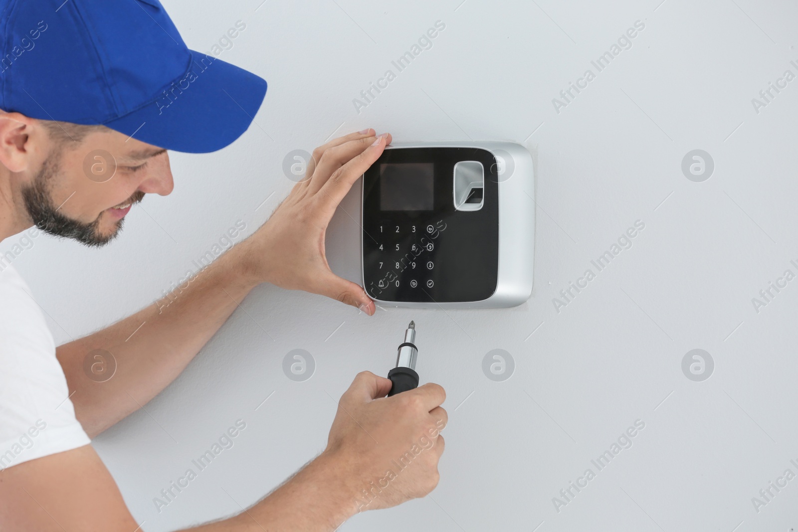 Photo of Male technician installing alarm system indoors