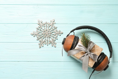 Photo of Flat lay composition with gift box and headphones on wooden background. Christmas music concept