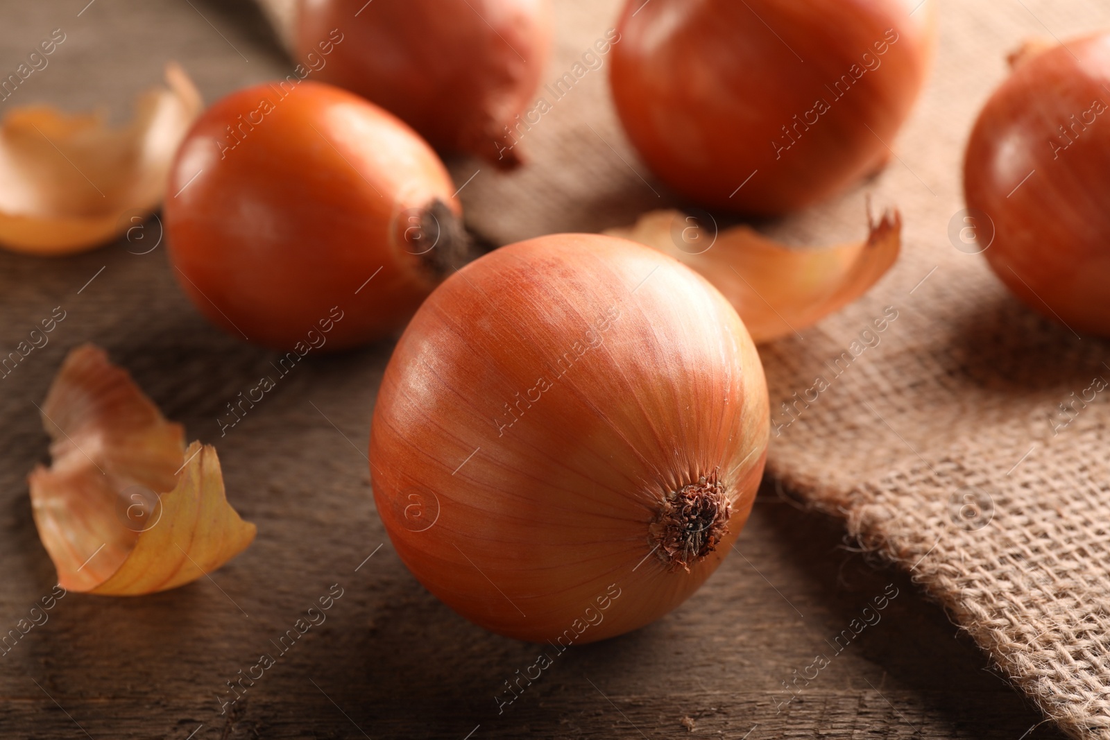 Photo of Many ripe onions on wooden table, closeup