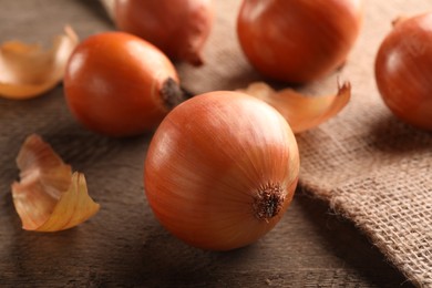 Many ripe onions on wooden table, closeup