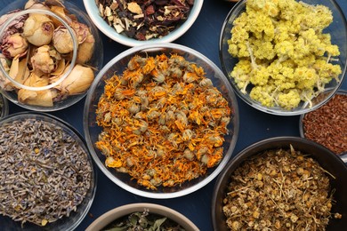 Photo of Many different dry herbs and flowers on blue table, flat lay