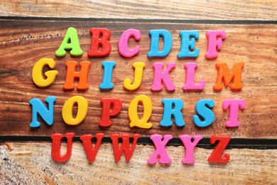 Photo of Colorful magnetic letters on wooden table, flat lay. Alphabetical order