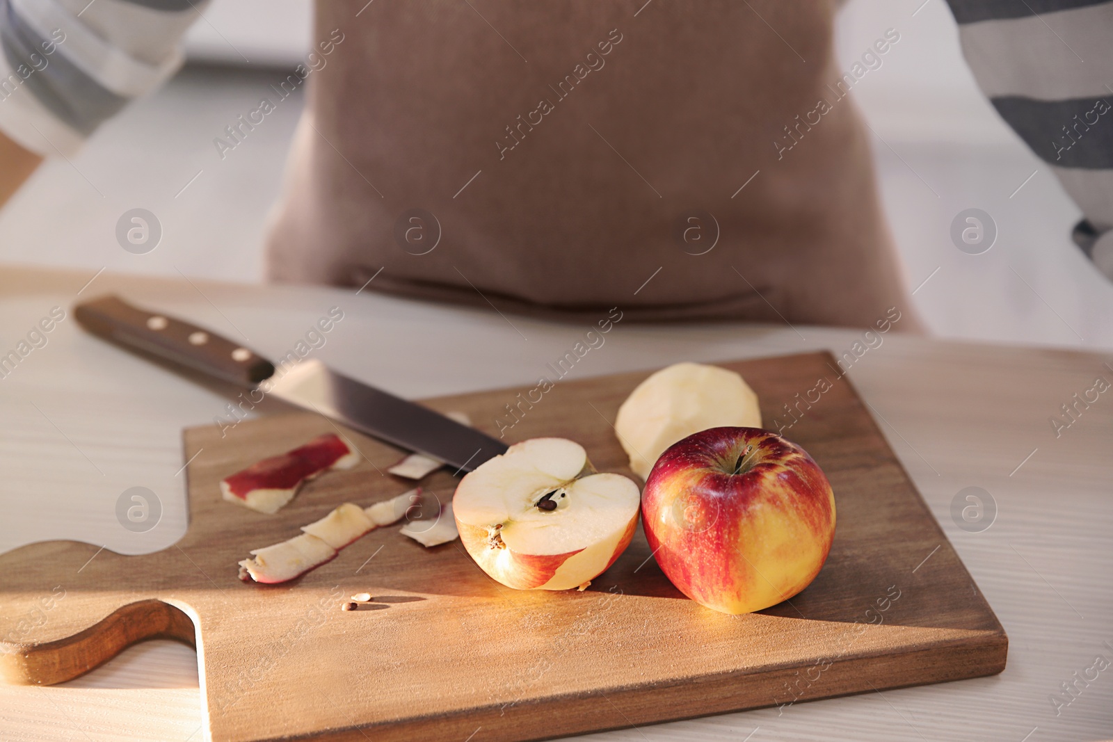 Photo of Cutting board with apples and blurred woman on background