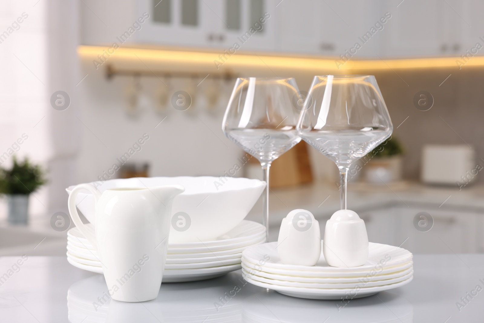 Photo of Set of clean dishware and glasses on table in kitchen