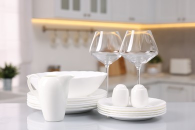 Set of clean dishware and glasses on table in kitchen