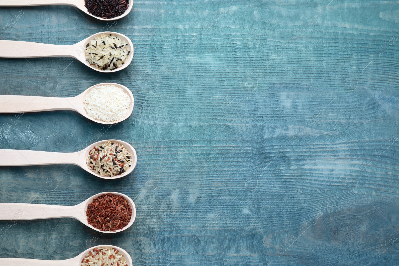 Photo of Flat lay composition with brown and polished rice on blue wooden table. Space for text