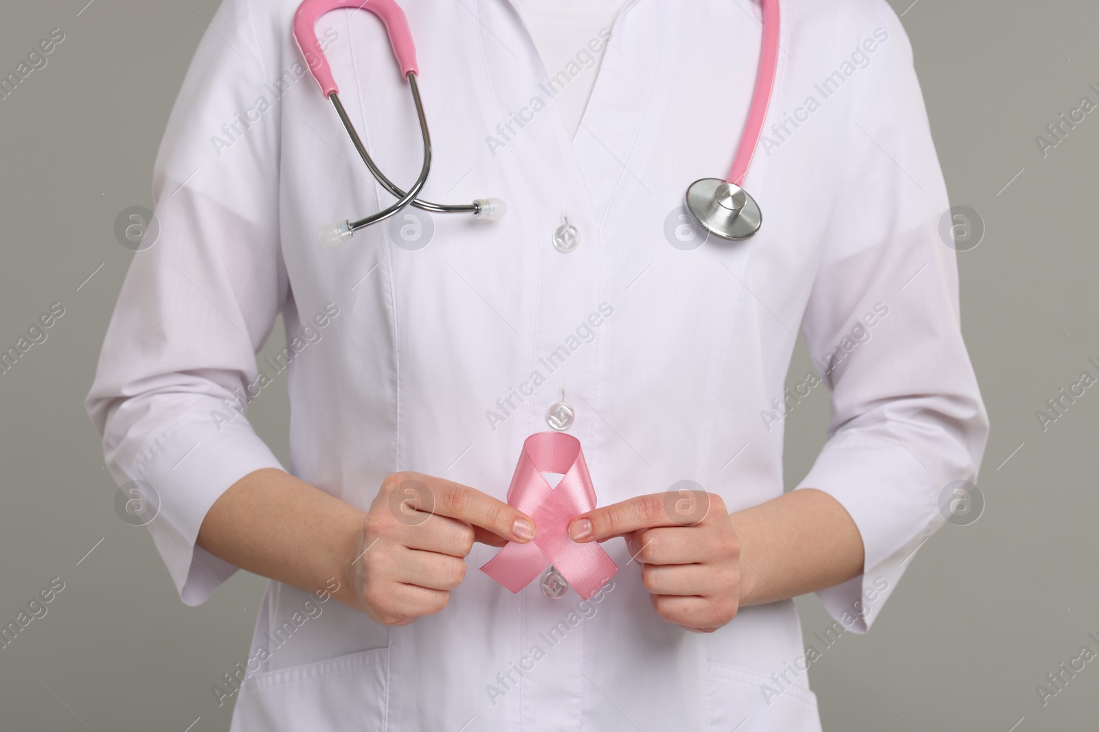 Photo of Mammologist with pink ribbon on gray background, closeup. Breast cancer awareness