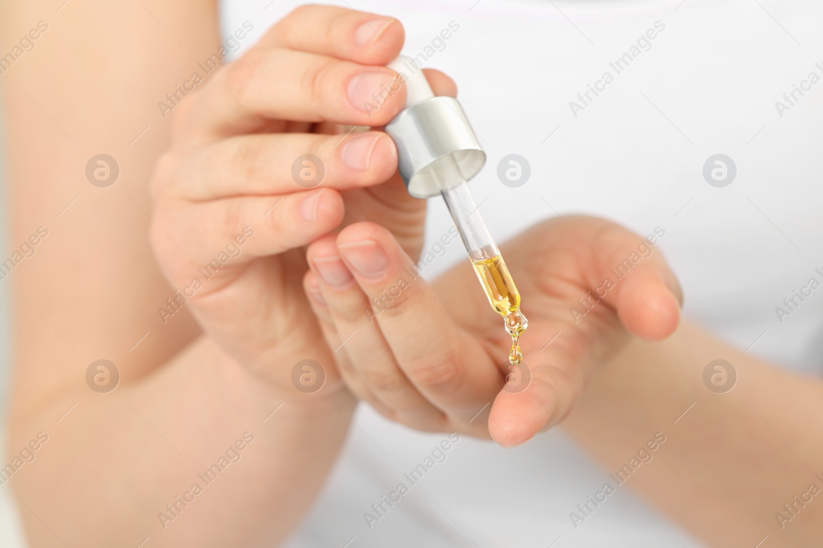 Photo of Woman applying essential oil onto hand, closeup