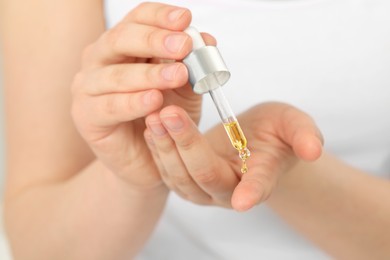 Woman applying essential oil onto hand, closeup