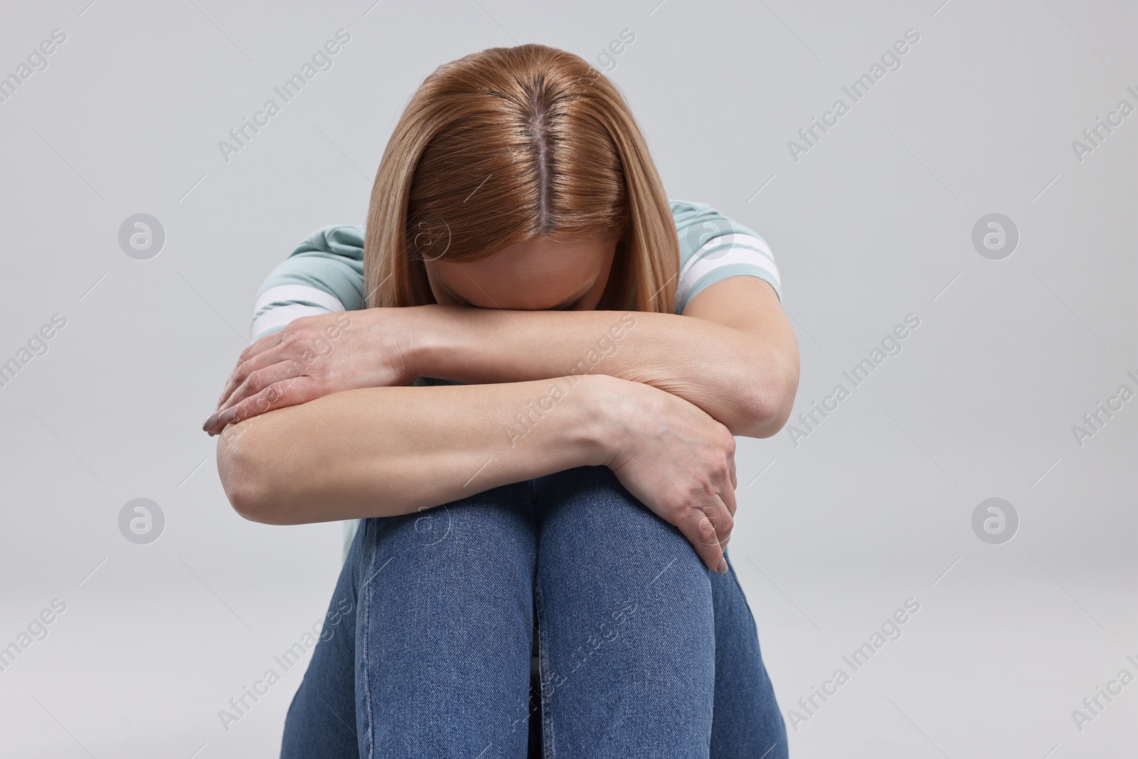 Photo of Sad woman hiding face on grey background