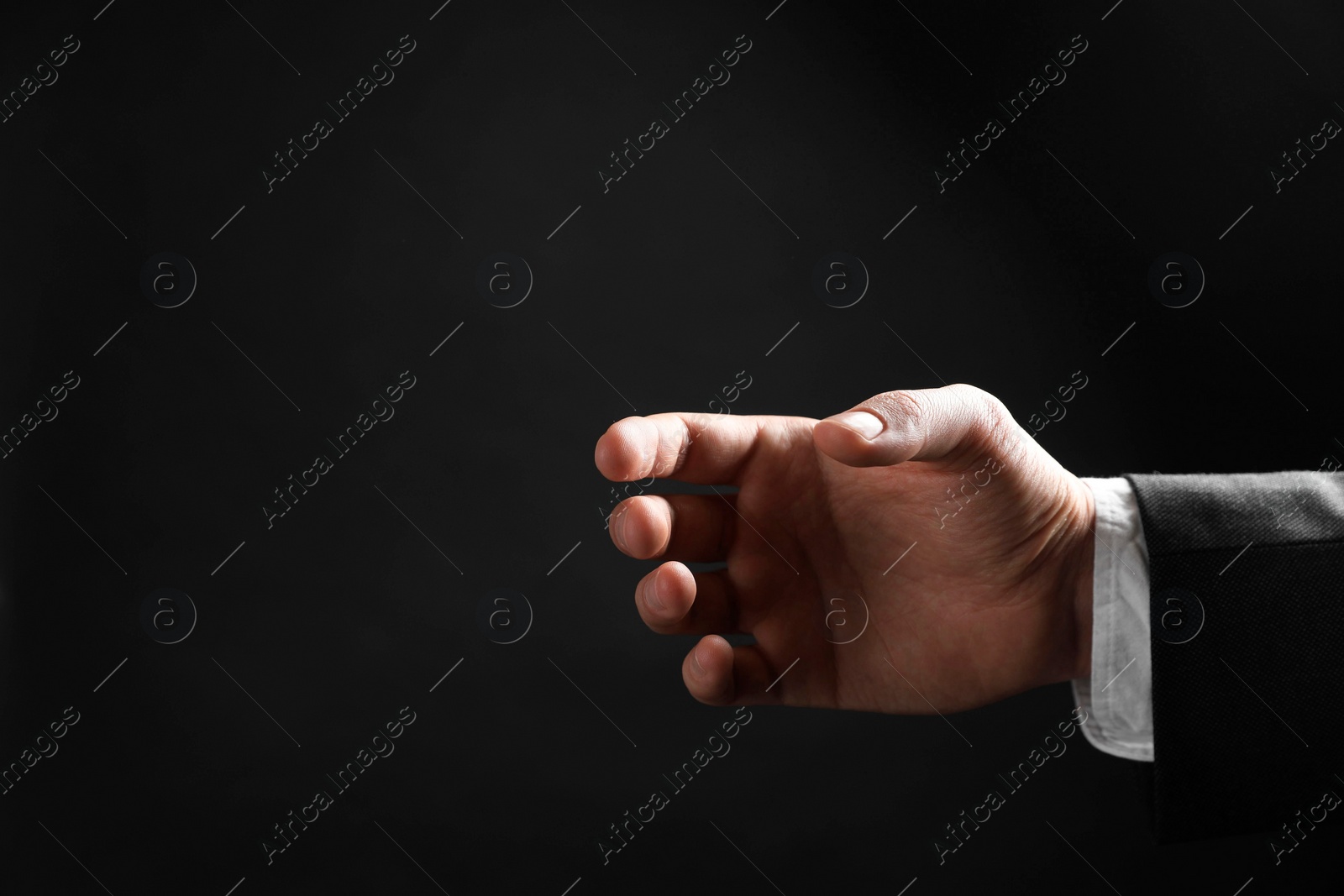 Photo of Man holding something in hand on black background, closeup. Space for text