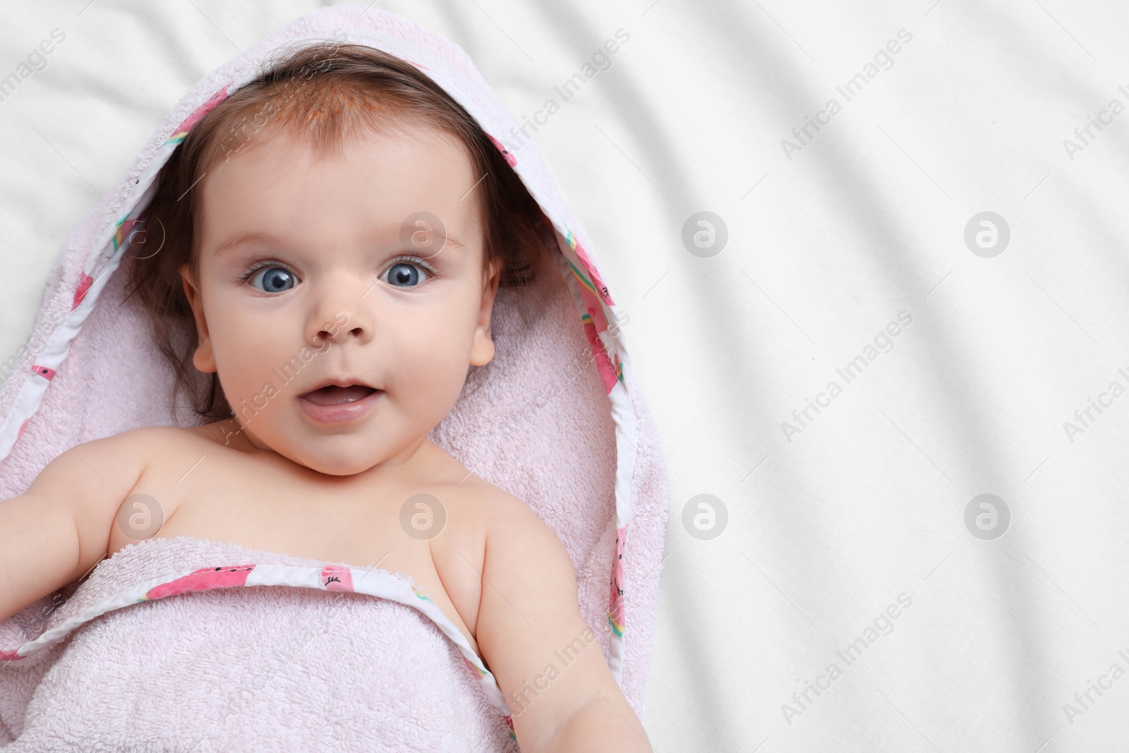 Photo of Cute little baby in hooded towel after bathing on bed, top view. Space for text