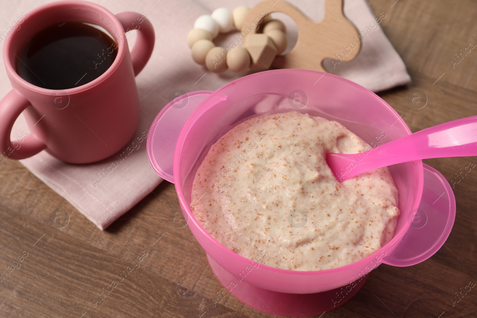 Photo of Baby food. Puree in bowl, drink and toy on wooden table