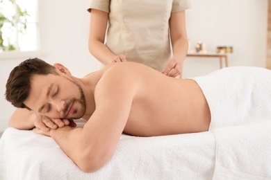 Handsome man receiving back massage in spa salon