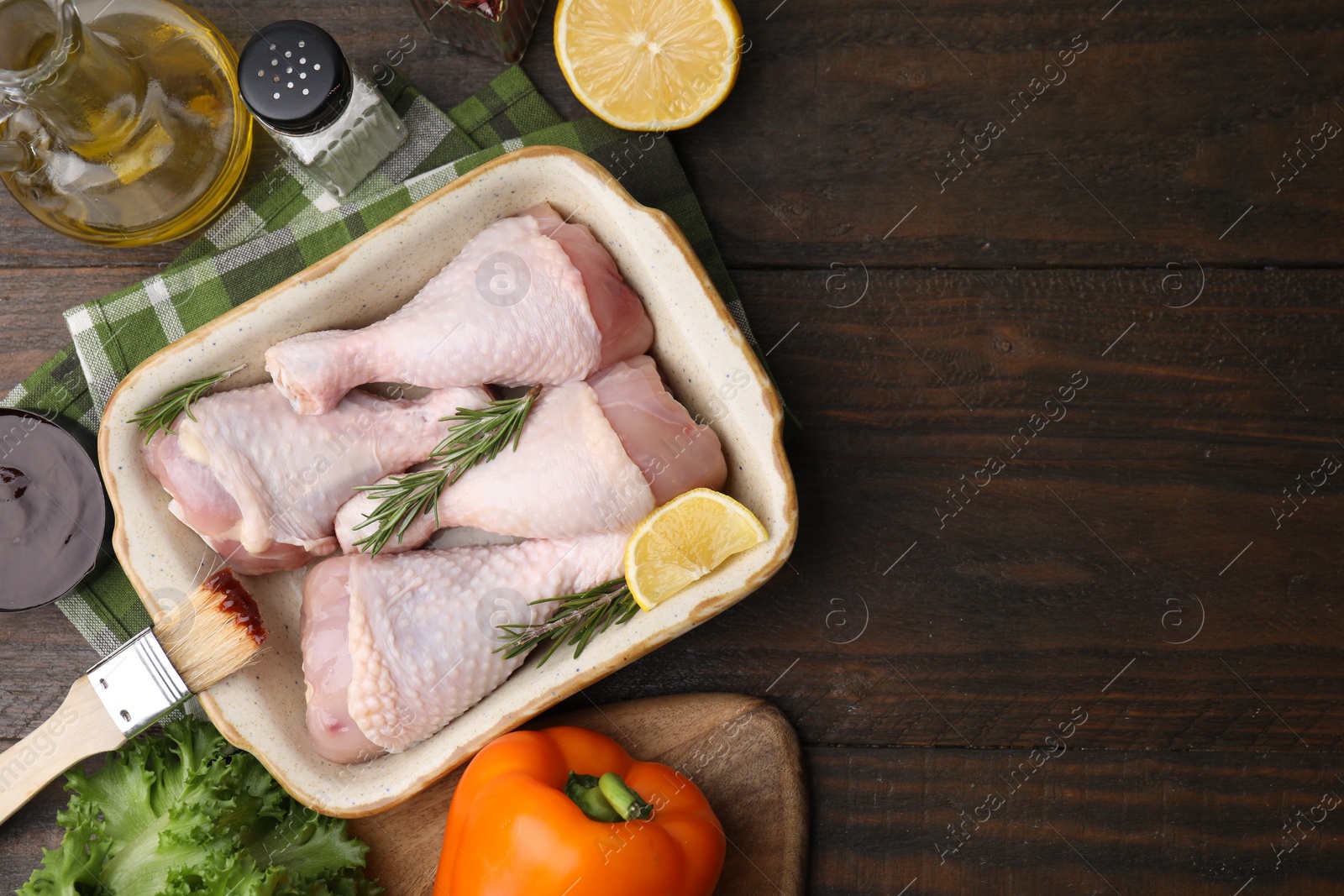 Photo of Flat lay composition with marinade and raw chicken drumsticks on wooden table. Space for text